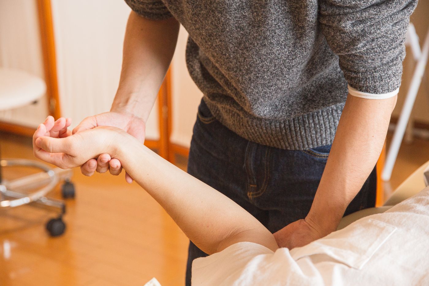 A therapist performing gentle hands-on manual therapy on a client's arm